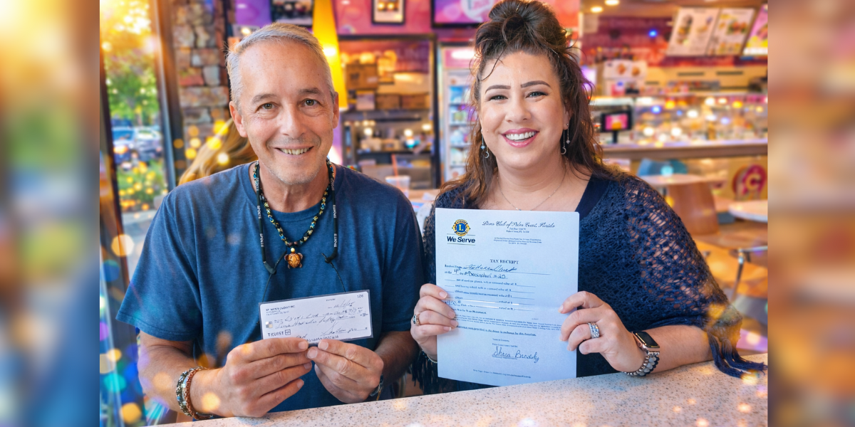 tephan Curcio presents a $750 donation to the Palm Coast Lions Club during a local meeting, standing alongside Shara Brodsky, President of the Palm Coast Lions Club, inside a Palm Coast ice cream shop. The moment reflects community support, local giving, and collaboration facilitated by PalmCoastLocal.com.